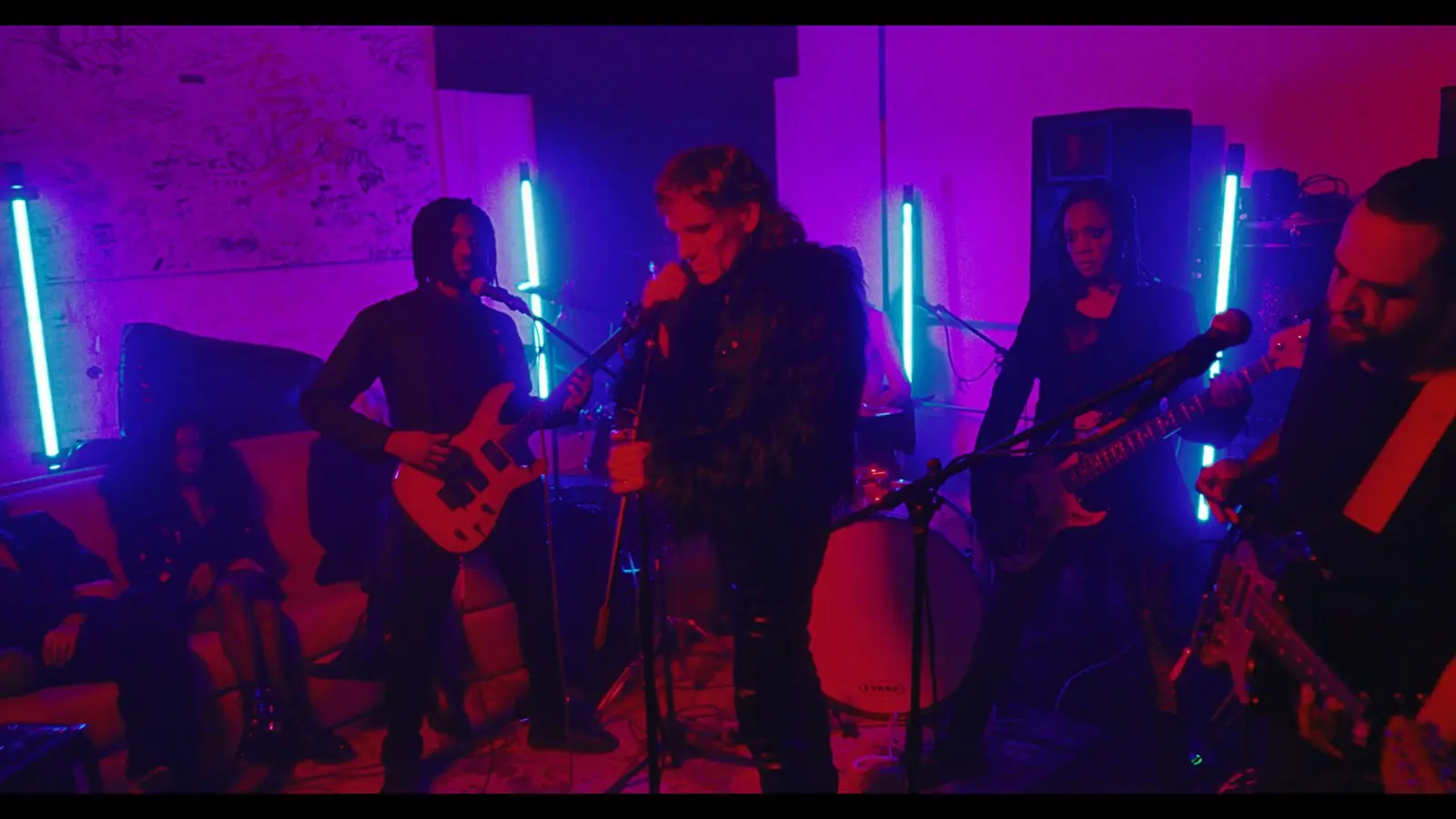JRNXLST tocando con la banda bajo luces púrpura y azules